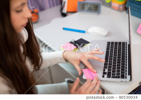 A teenager sticks a card on her laptop while learning English. A teenager sticks a card on her laptop while learning English. 90530034
