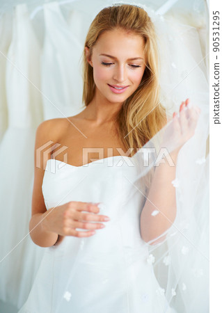 Thinking of her future with excitement. A young bride trying on a wedding dress. 90531295