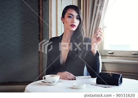Luxury and style. Shot of a woman smoking a cigarette in a luxurious setting wearing classicly elegant attire. Luxury and style. Shot of a woman smoking a cigarette in a luxurious setting wearing classicly elegant attire. 90531620
