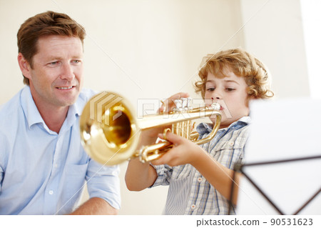 Proud of his little trumpet player. Shot of a cute little boy playing the trumpet while his father watches him proudly. Proud of his little trumpet player. Shot of a cute little boy playing the trumpet while his father watches him proudly. 90531623