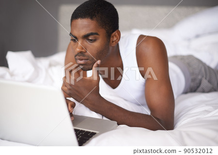 Connected in the morning. Shot of a young man in bed using a laptop. 90532012