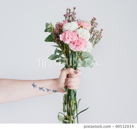 These flowers represents pure love and admiration. Studio shot of an unrecognizable woman holding a bunch of flowers against a grey background. 90532014