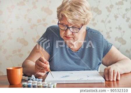 Attractive old woman painting by numbers at home. Inspirational hobby and art therapy. Selective focus 90532310
