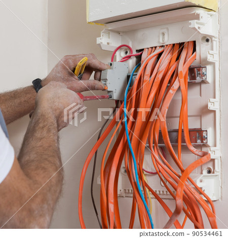 installation of an electrical panel, hands screwing the automatic switch 90534461