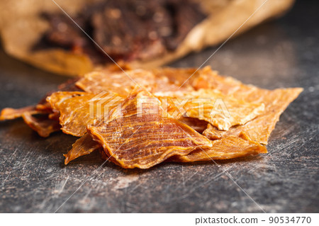 Turkey jerky meat. Dried sliced meat on black table. 90534770