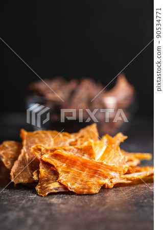 Turkey jerky meat. Dried sliced meat on black table. 90534771
