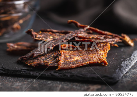 Beef jerky meat. Dried sliced meat on cuting board. 90534773