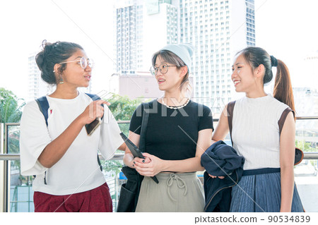 Three young multi-racial women smiling and talking to each other. 90534839