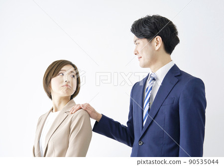 A businessman who grabs the shoulder of a business woman with a white background A businessman who grabs the shoulder of a business woman with a white background 90535044