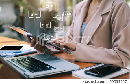 Businesswomen using tablet with laptop and document on desk with virtual interface graphic icons network diagram. 90535337