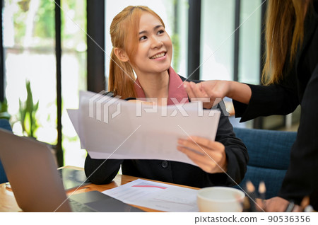 Female office worker employee smiling while talking with her friendly female boss. Female office worker employee smiling while talking with her friendly female boss. 90536356