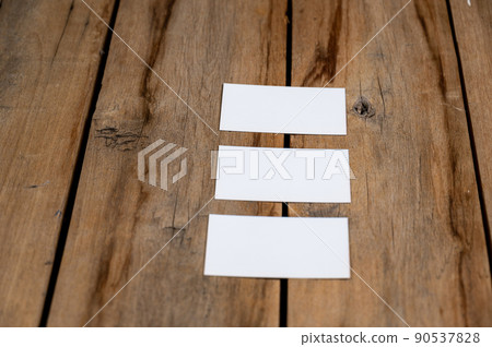 Three Blank business cards against a wooden background. White paper rectangles lie on top of old cracked boards. Selective focus. 90537828
