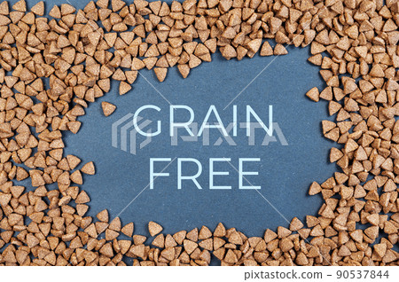 Dry cat food against a gray background. Pellets are triangular. Grain-free food for cats. Above title in capital letters in the center of the frame. Flatlay. 90537844
