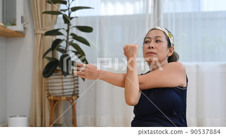 Shot of active senior lady doing stretching exercises during home workout. Healthy lifestyle concept Shot of active senior lady doing stretching exercises during home workout. Healthy lifestyle concept 90537884