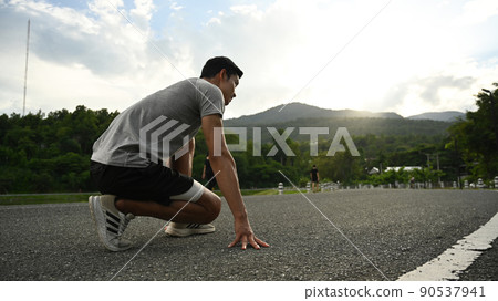 Young sportsman in starting position, ready to run outdoors in the morning. Health and sport concept Young sportsman in starting position, ready to run outdoors in the morning. Health and sport concept 90537941
