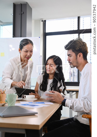Senior older female executive ceo and young employee discuss corporate project together at briefing Senior older female executive ceo and young employee discuss corporate project together at briefing 90537942