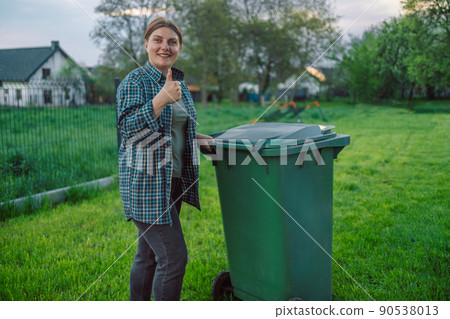European 20s girl take out the trash can sorting garbage near a home European 20s girl take out the trash can sorting garbage near a home 90538013