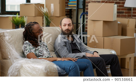 Exhausted life partners taking break after moving boxes in apartment, relaxing on couch and celebrating home investment. Feeling tired about decorating new real estate property. Exhausted life partners taking break after moving boxes in apartment, relaxing on couch and celebrating home investment. Feeling tired about decorating new real estate property. 90538661