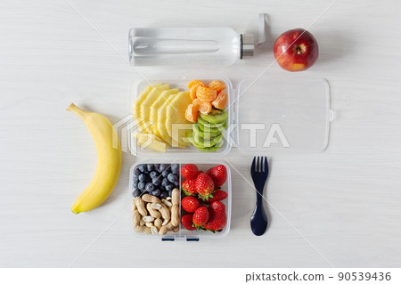 Various raw fruits and berries in a lunch box top view. Healthy eating, vegan food concept. Various raw fruits and berries in a lunch box top view. Healthy eating, vegan food concept. 90539436