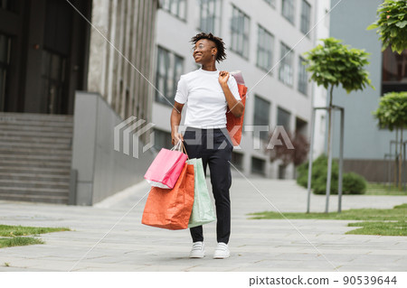 Young happy smiling fashionable African American woman, holding paper shopping bags 90539644