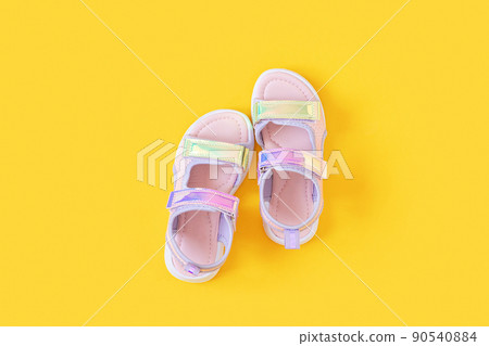 Stylish holographic sandals for kids on yellow background. Shiny fashion summer shoes. Flat lay, Top view 90540884
