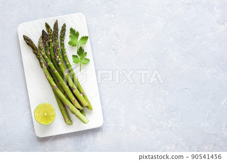 Asparagus stems on the rectangular plate served with green lemon and parsley Asparagus stems on the rectangular plate served with green lemon and parsley 90541456