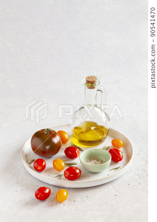 Round tray with different tomato varieties, salt and olive oil Round tray with different tomato varieties, salt and olive oil 90541470