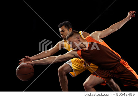 Portrait of two concentrated men, basketball players in motion, dribbling isolated over black studio background 90542499