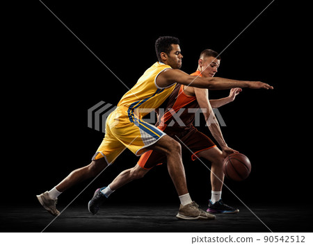 Portrait of two sportive men, basketball players in uniform playing, training isolated on black studio background. Following the ball carrier. Portrait of two sportive men, basketball players in uniform playing, training isolated on black studio background. Following the ball carrier. 90542512