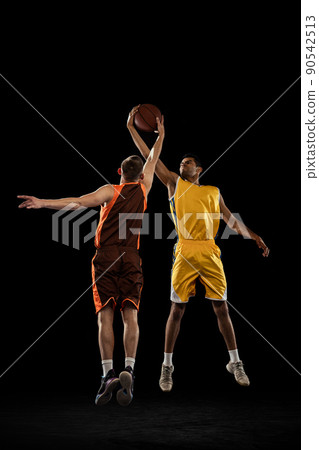 Dynamic shot of two professional basketball players in motion, in a jump, training isolated over black studio background. Jump pass Dynamic shot of two professional basketball players in motion, in a jump, training isolated over black studio background. Jump pass 90542513