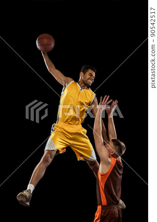 Dynamic portrait of two young men, professional basketball players in motion, training isolated on black studio background. Jump shot Dynamic portrait of two young men, professional basketball players in motion, training isolated on black studio background. Jump shot 90542517
