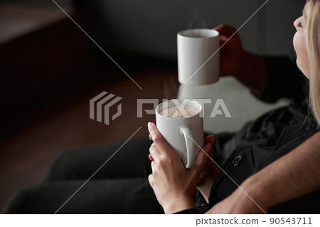 image of a man and a woman in love with cups of coffee sitting on the sofa. image of a man and a woman in love with cups of coffee sitting on the sofa. 90543711