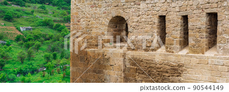 fragment of the wall of a medieval castle, behind which the faubourgs are visible; Naryn-Kala citadel in Derbent 90544149