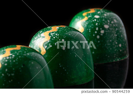 Luxury handmade chocolate candies on black background. Green candies with multicolored drops. Product concept for chocolatier. Close-up Luxury handmade chocolate candies on black background. Green candies with multicolored drops. Product concept for chocolatier. Close-up 90544259