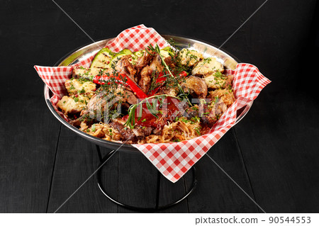Assorted delicious grilled meat with vegetables and bbq sauce on an iron tray on black background close up. Big set of Hot Meat Dishes. Top view Assorted delicious grilled meat with vegetables and bbq sauce on an iron tray on black background close up. Big set of Hot Meat Dishes. Top view 90544553