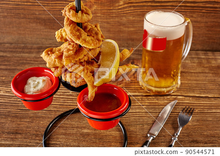 Squid rings in batter with lemon, red and white sauces on wooden table 90544571