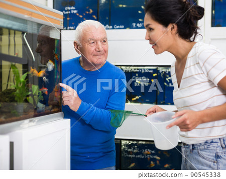 Pet shop employee helps an mature man choose an aquarium fish Pet shop employee helps an mature man choose an aquarium fish 90545338