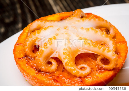 Seafood. Small octopus baked on an orange slice. Close-up Seafood. Small octopus baked on an orange slice. Close-up 90545386