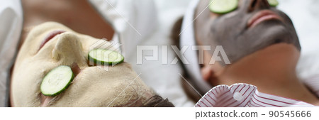 Woman and man friends resting on bed with facial mask and cucumbers Woman and man friends resting on bed with facial mask and cucumbers 90545666