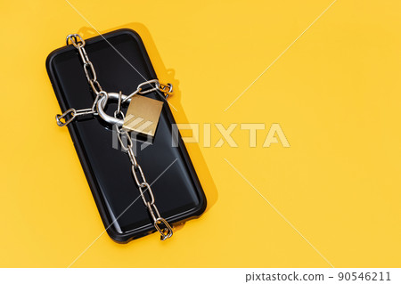 Phone security concept. Smartphone locked with chain and padlock on yellow background. Mobile security and data privacy 90546211