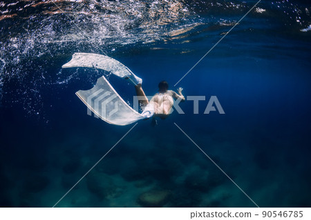 Woman with white freediving fins swim in surface underwater in ocean 90546785