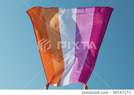 woman is holding a lesbian pride flag outdoors 90547173