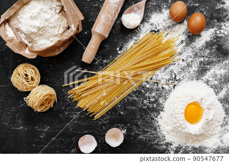 Raw egg pasta with flour on black background Raw egg pasta with flour on black background 90547677