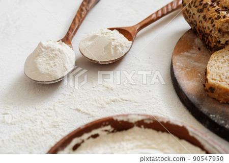 Pile of flour in wooden spoon on white background Pile of flour in wooden spoon on white background 90547950