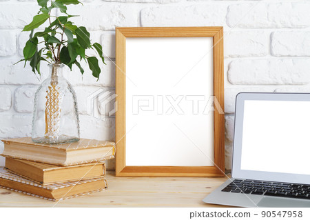 Blank picture frame on wooden table with books and laptop Blank picture frame on wooden table with books and laptop 90547958