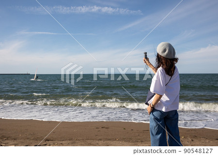 A woman shooting a video at the beach A woman shooting a video at the beach 90548127