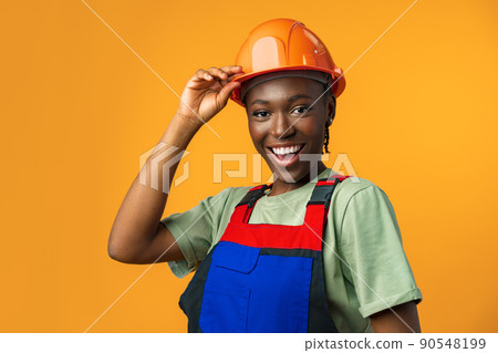 Young african american woman wearing architect hardhat against yellow background 90548199