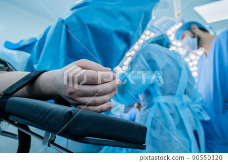 Hand of a patient lying on the operating table. The patient is sleeping under general anesthesia.  90550320