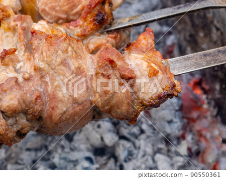 Juicy slices of pork meat are strung on skewers and grilled in charcoal grill. Juicy slices of pork meat are strung on skewers and grilled in charcoal grill. 90550361