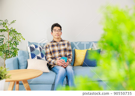 一個男人拿著杯子在沙發上放鬆 一個男人拿著杯子在沙發上放鬆 90550735